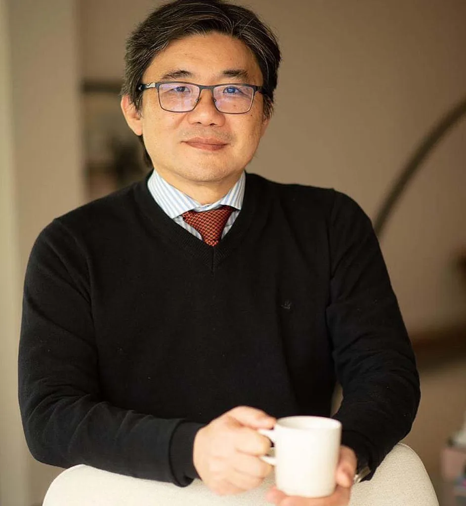 Dr. Flávio Iizuka, urologista, sentado com uma xícara de café